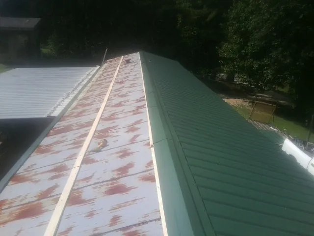 Old rusted panels beside newly installed green metal roofing — Wind Damage Roof Repair by Roofing Brothers in Waynesboro