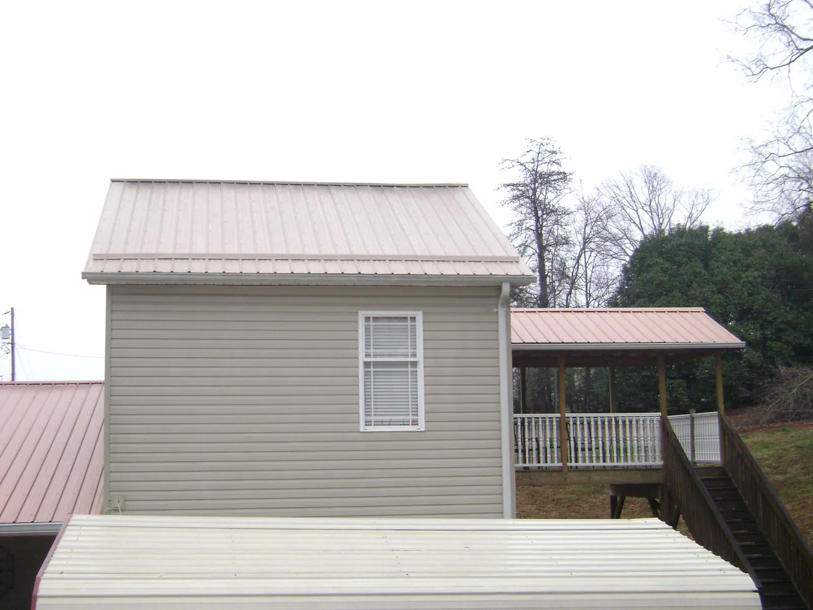 Tan metal roofs on a two story addition and attached porch, from a Roof Replacement job in Waynesboro